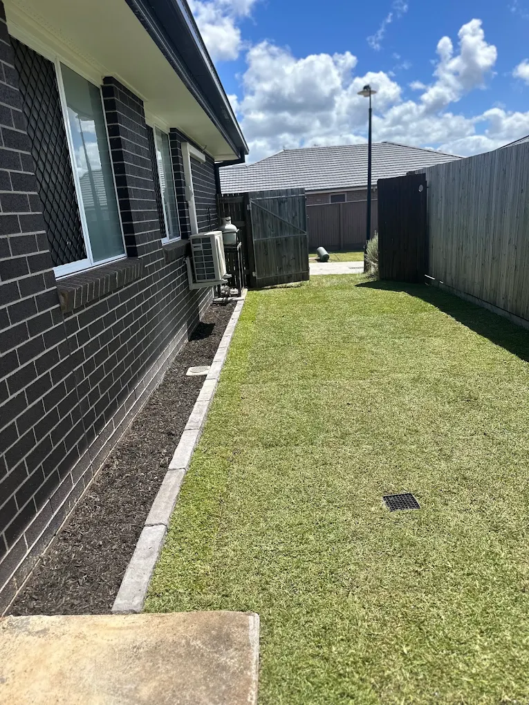 Timber retaining wall with white pebble garden bed and pencil pines